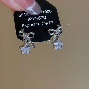 Detail of silver bow and star stud earrings featuring micro-pave cubic zirconia crystals