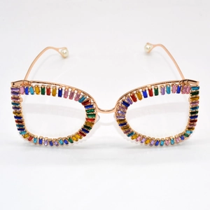 Cat eye sunglasses with gold metal frame and colorful rhinestones on white background