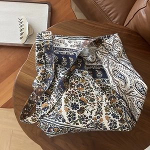 Detail of bohemian printed canvas bag featuring ethnic floral patterns on a wooden table