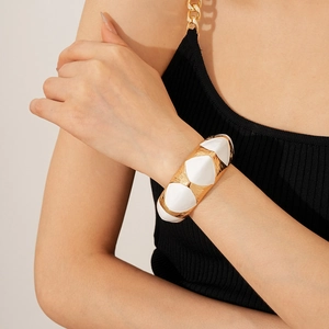Detailed macro view of vintage hammered gold cuff with white enamel inlay for women