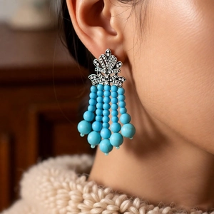 Détail de boucles d'oreilles vintage avec strass et pompons de perles turquoise