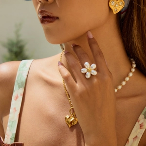 Elegant floral pearl ring and golden heart jewelry set worn by a model in close-up