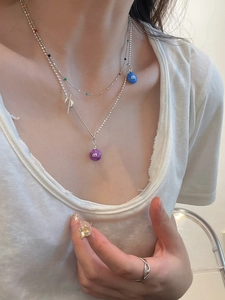 Detail of s925 silver necklace with colorful beads and 'm' candy letter pendants on model