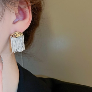Detail of mixed metal tassel earrings with hammered gold stud and silver link chains