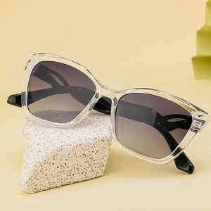 Fashionable cat eye sunglasses with clear frames and gradient lenses on a textured rock