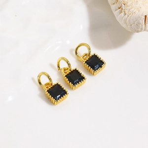 Macro shot of three gold-plated square charms with black cubic zirconia for DIY jewelry