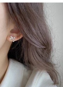 Close-up of elegant S925 sterling silver bow knot stud earrings worn by a model