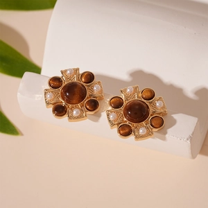 Detailed close-up of retro cross earrings with brown stones and white pearls on gold