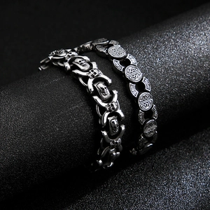 Dettaglio macro dei ciondoli a teschio e motivi sbalzati su bracciali punk in acciaio