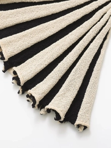Détail du tissu en maille rayée noir et beige avec une texture douce bouclée