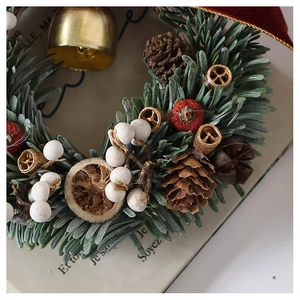 Detail of Christmas wreath with pine needles, cones, berries, bells and dried orange