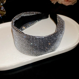 Detail of a luxury wide headband with silver rhinestones on a black fabric base