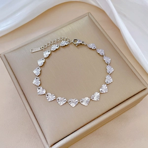 Close-up of heart-shaped stainless steel links with sunburst texture and S.STEEL hallmark