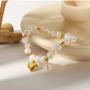 Detail view of Baroque freshwater pearls with a gold heart pendant on white ceramic
