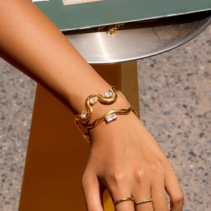 Détail d'un bracelet manchette doré ondulé avec des pierres en zircon brillant sur un poignet