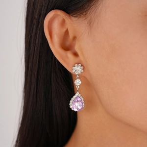 Close-up of elegant silver drop earrings with purple teardrop crystals on female model