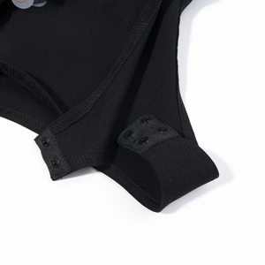 Detail view of the secure snap closure at the bottom of the black V-neck bodysuit