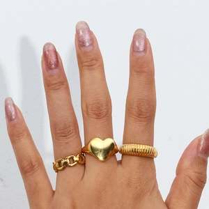 Close-up of a 3-piece set of gold-plated rings with heart, chain, and twisted textures