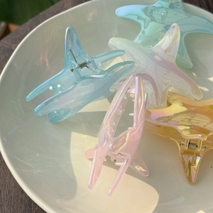 Macro detail of iridescent starfish hair claws in pastel blue, pink, and yellow colors