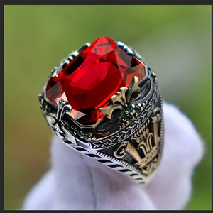 Macro shot of luxury vintage men's ring featuring a large red gemstone and ornate silver carvings