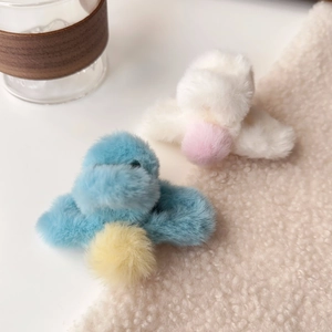 Close-up of plush faux fur hair claws with colorful pom poms in blue and white colors