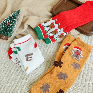 Close-up of thick festive coral fleece socks with Christmas patterns on soft wool background