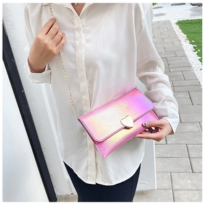 Close-up of a holographic heart-shaped metal lock and gold chain on a pastel purse