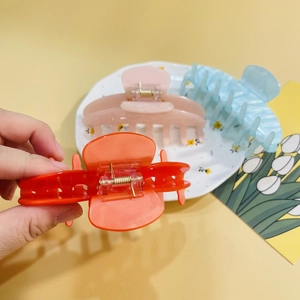 Detailed view of large acrylic shark hair claws in orange, pink and light blue colors
