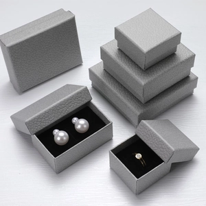 Detailed view of grey leather jewelry boxes with various sizes on a white wood background