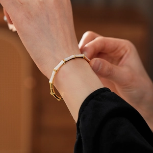 Detailed view of a gold-plated bamboo joint bracelet with white enamel on a wrist