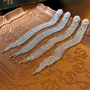 Detailed close-up of long tassel earrings with sparkling rhinestones in gold and silver