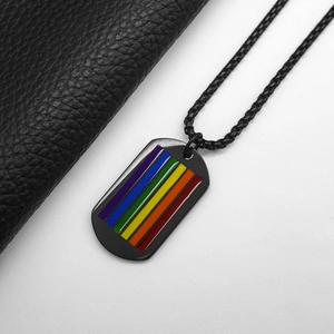 Detail of black military tag necklace with rainbow flag inlay on leather texture