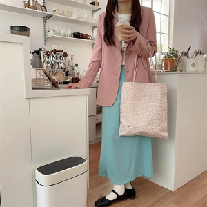Détail du sac cabas en toile à fleurs tenu par un mannequin dans un café chic