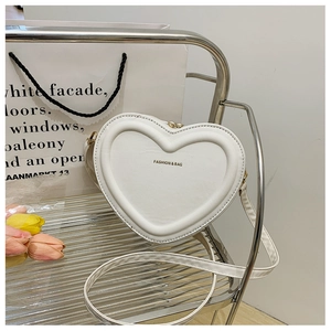 Dettaglio della borsa a tracolla a forma di cuore in pelle color crema su metallo
