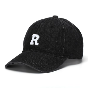 Close-up of white embroidered letter R on black denim vintage baseball cap material