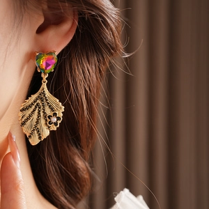 Detail of vintage gold earrings with heart-shaped gemstone and pearl floral accents