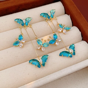 Gros plan d'un ensemble de boucles d'oreilles papillon dorées avec cristaux bleus