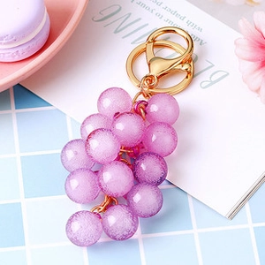 Macro detail of purple grape keychain with sparkling texture and golden metal ring
