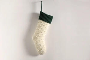 Detail of chunky knit Christmas stocking in cream and green with textured fish scale pattern