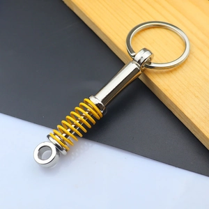 Close-up of metal car shock absorber keychain with yellow spring and polished finish