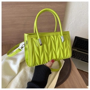 Close-up of neon green quilted handbag with silver hardware and detachable shoulder strap