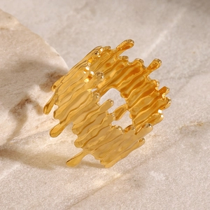 Detail of gold lava texture open ring with irregular organic lines on stone background