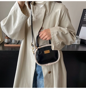 Detail of black mini pillow bag featuring white faux fur trim and gold-tone logo hardware
