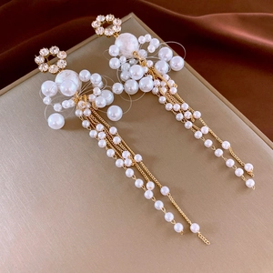 Detailed view of pearl tassel earrings with golden chains on a luxury silk background