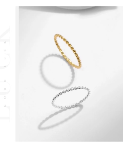 Detail view of intertwined twisted silver and gold rope rings on a white background