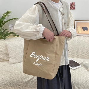 Close-up of khaki canvas tote bag with Bonjour magic print in a cozy home setting