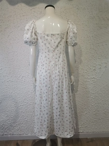 Detail view of the back zipper and floral puff sleeve dress on a white background