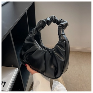 Detailed close-up of the black pleated handle and soft ruched texture on the baguette bag