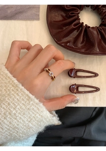 Close-up of a zircon chain ring with amber and blue accents on a hand with accessories