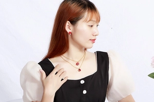 Close-up of a model wearing a red round pendant necklace and matching stud earrings set